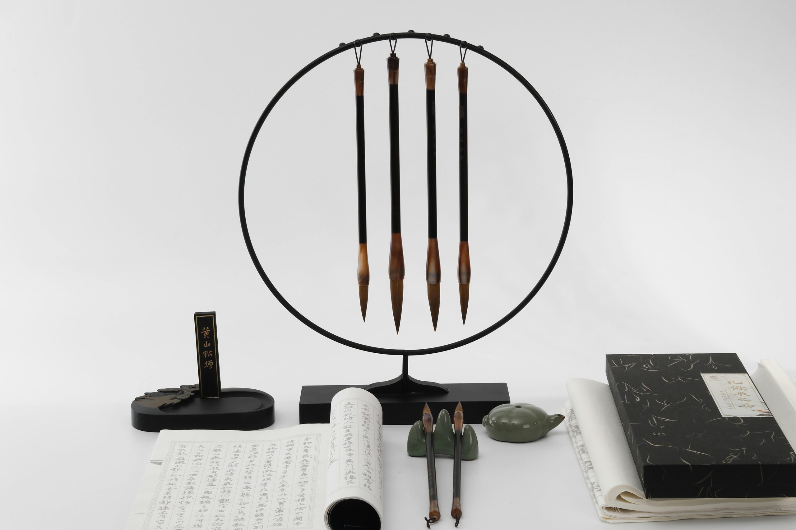 Traditional Chinese calligraphy brushes displayed on a decorative stand with ink stone and practice sheets
